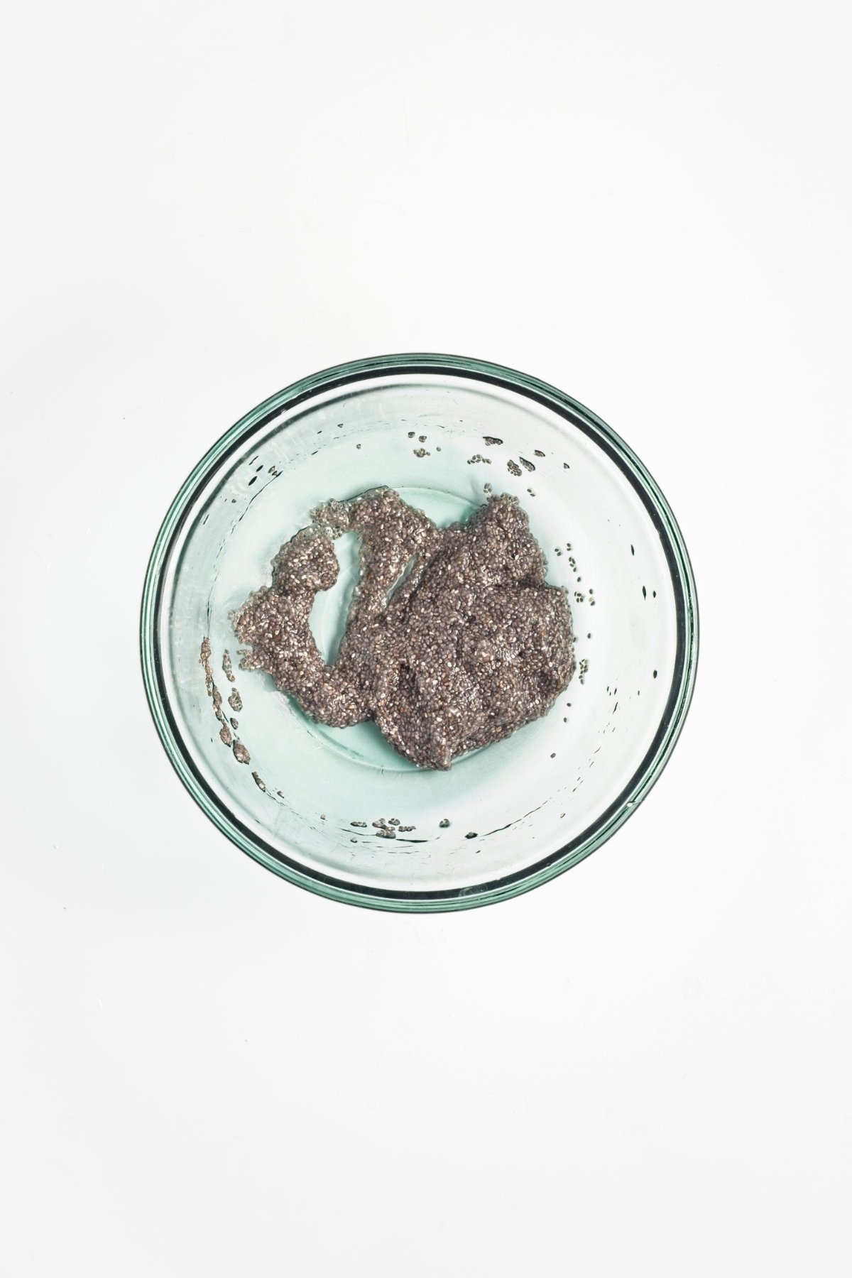Chia seeds thickened into a gel after soaking in water in a glass mixing bowl.