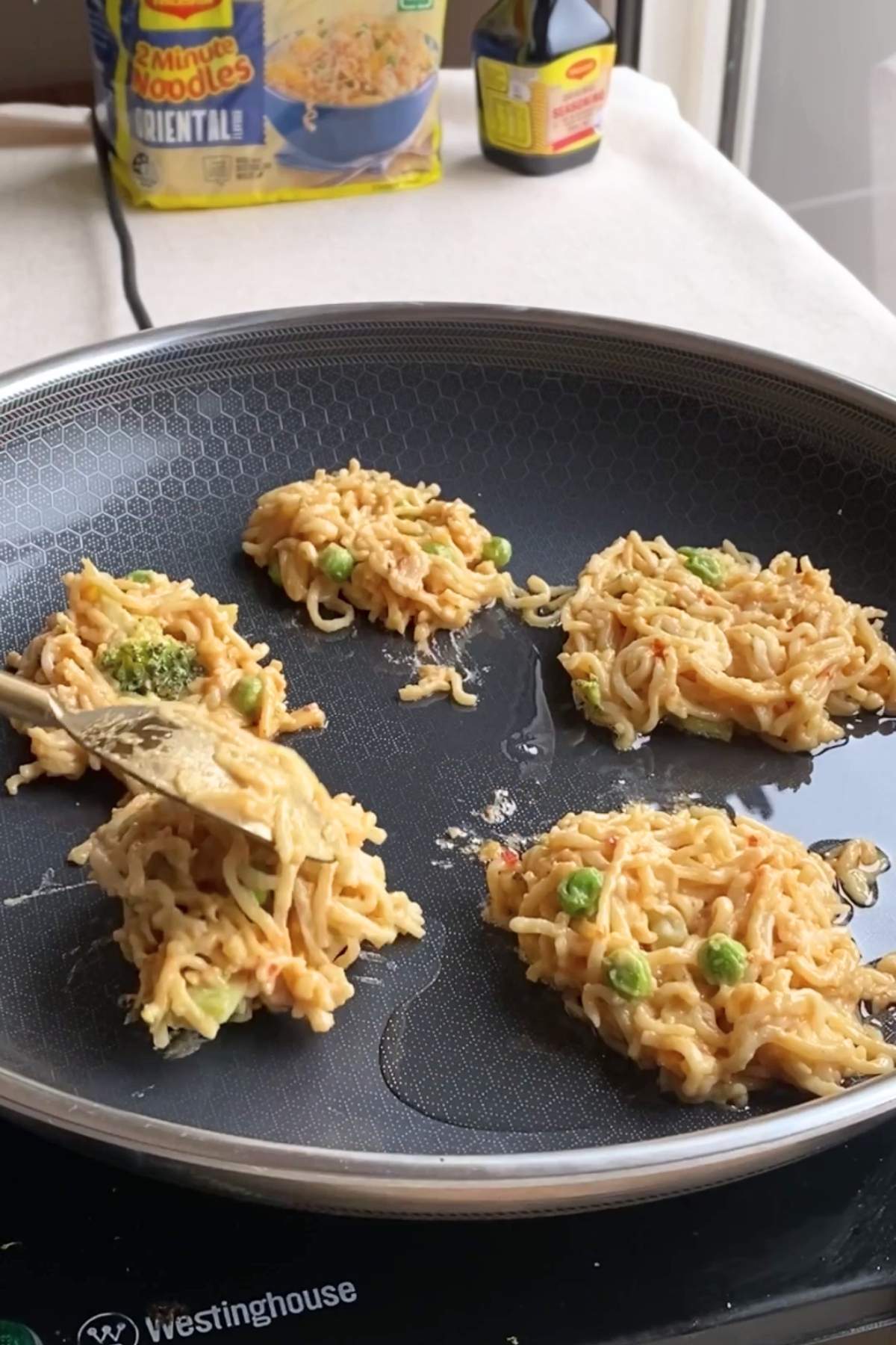 Noodle mixture spooned into a frying pan.
