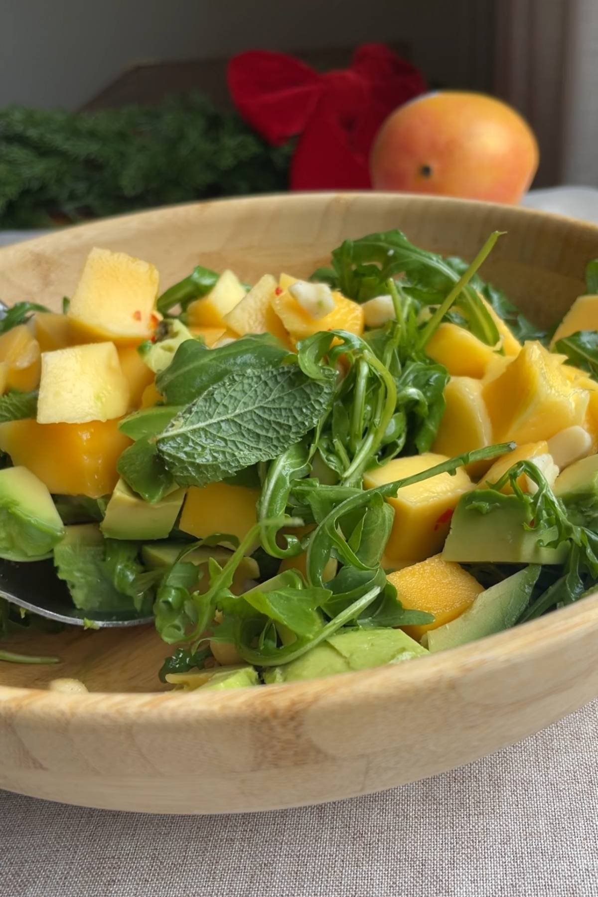Close-up of arugula, mango and avocado scooped with a serving spoon.