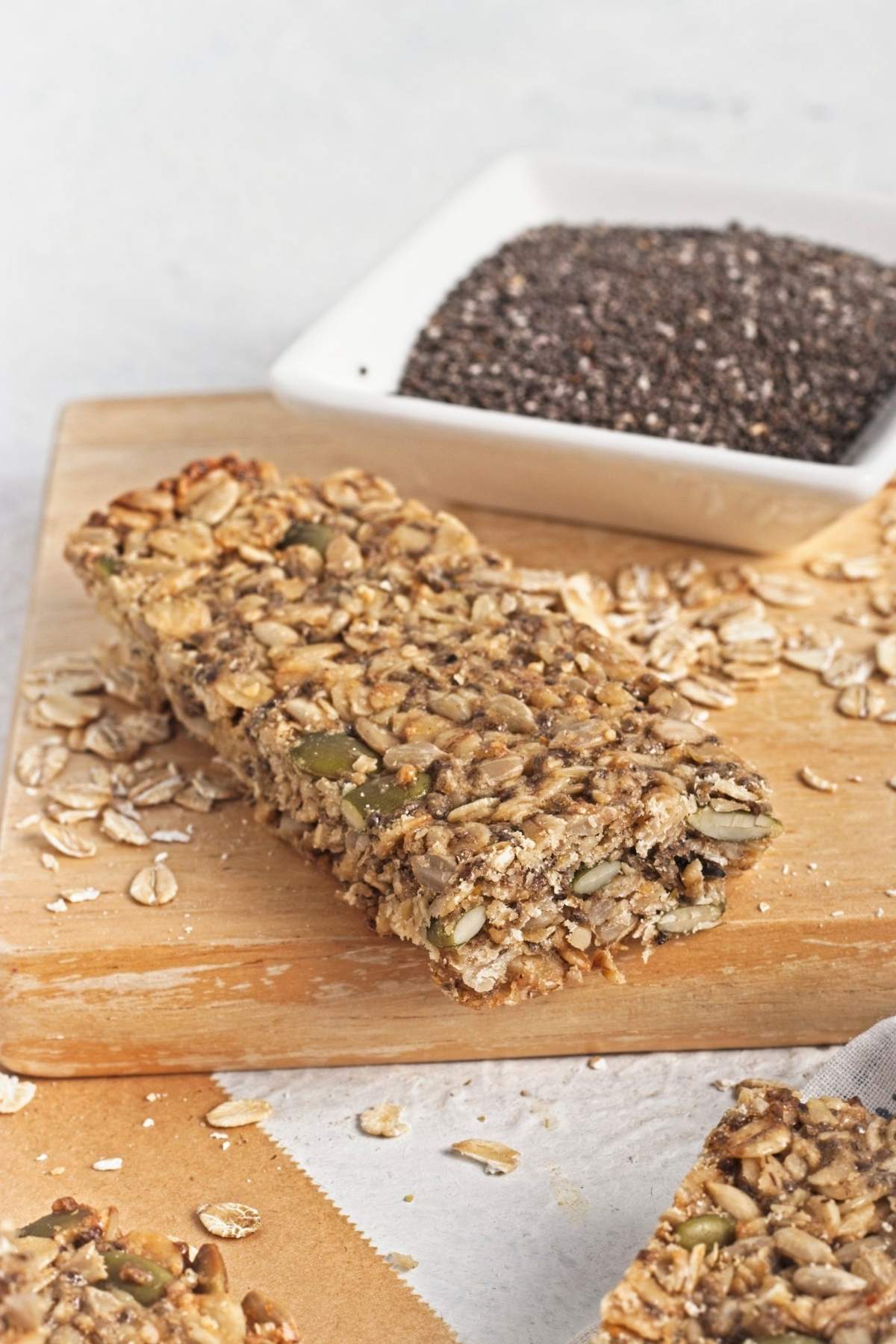 Close-up of a single granola bar on a wooden board with visible oats, seeds, and chia.