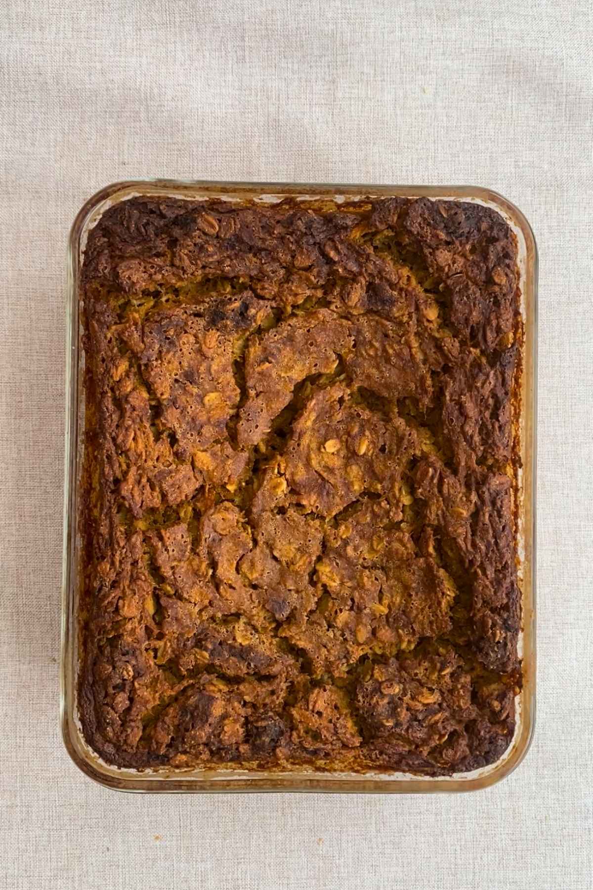 Golden-brown baked oats with a textured, crisp top in a rectangular glass dish.
