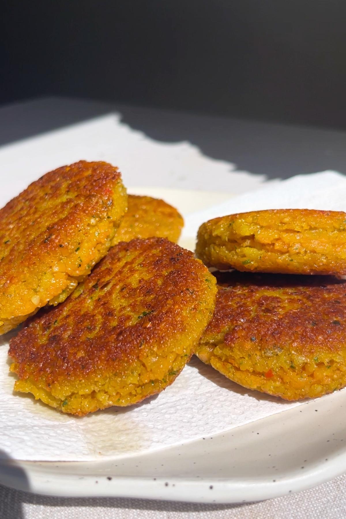 Golden lentil fritters resting on a white plate lined with paper towel.