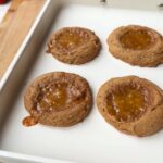 Four caramel-filled cookies cooling on a tray.