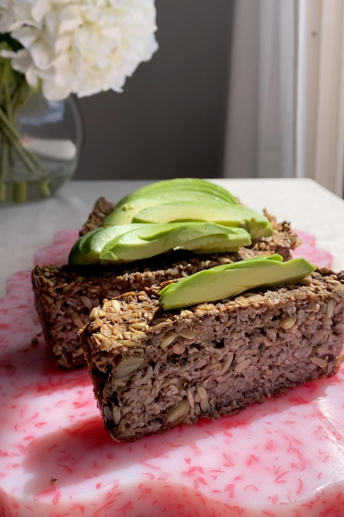 Sliced seeded loaf with avocado arranged neatly on top.