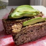 Close-up of seeded loaf slices topped with creamy avocado.