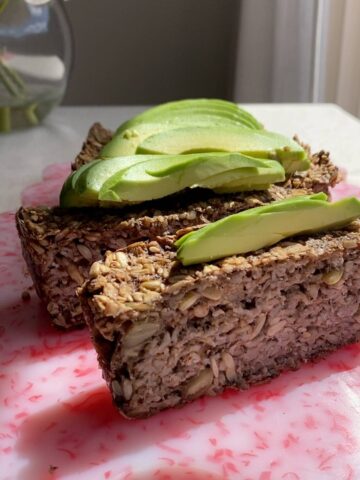 Close-up of seeded loaf slices topped with creamy avocado.