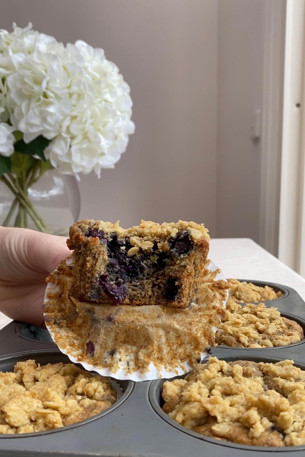 Blueberry breakfast muffin broken in half showing moist crumb and whole blueberries inside.