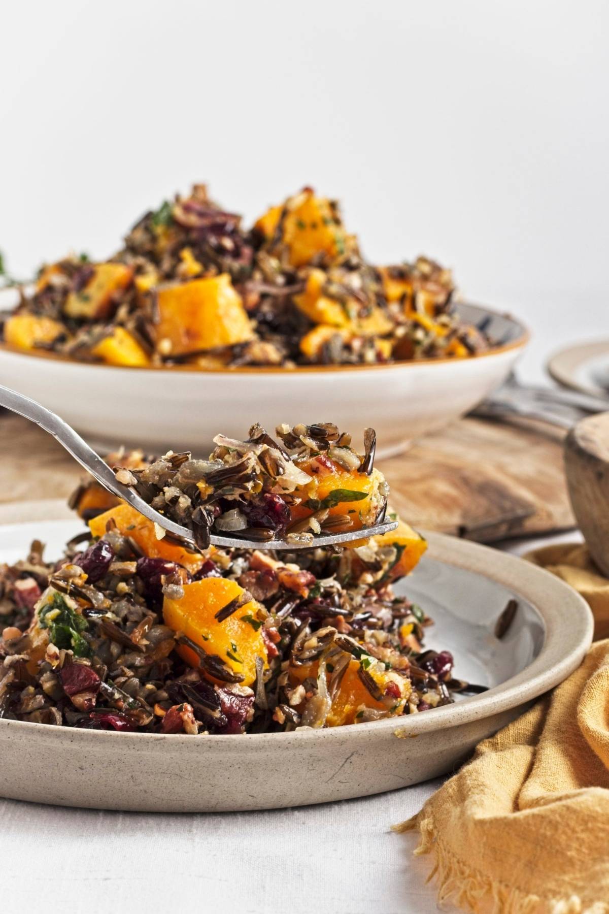 Spoon lifting a serving of wild rice salad with roasted butternut and cranberries.