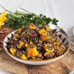 Wild rice salad with roasted butternut, cranberries, and pecans arranged in a bowl.