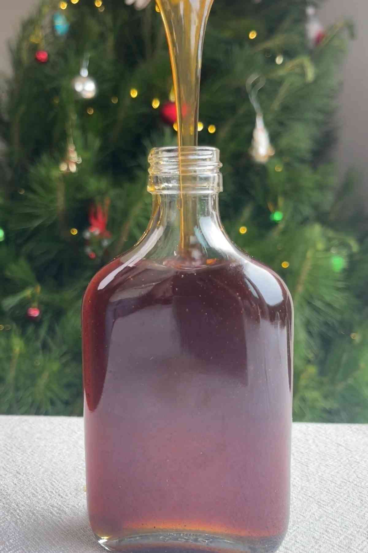 Thick syrup streaming into a glass bottle from above.