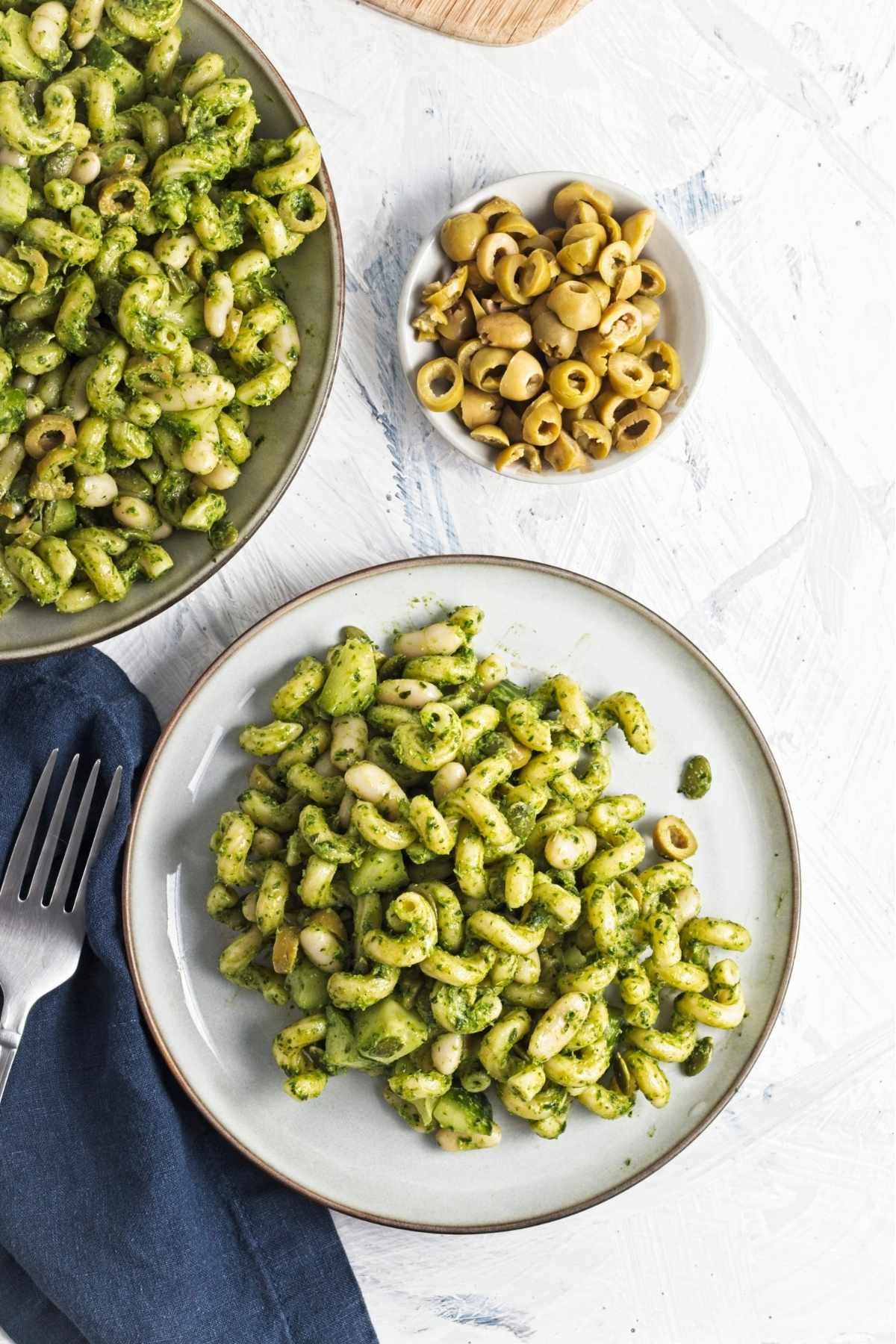 Overhead view of green goddess pasta salad in a bowl on a white surface.
