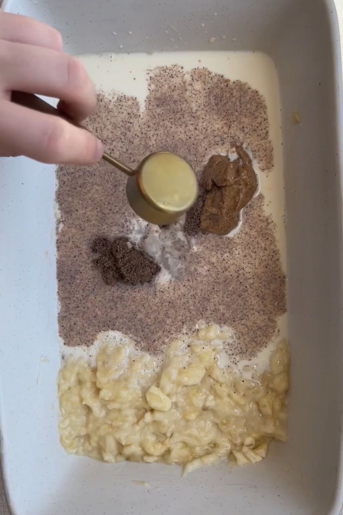 Milk, mashed banana, maple syrup, vanilla, and spices added to a baking dish.