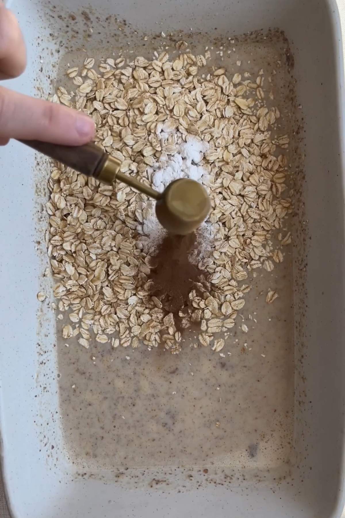 Rolled oats, baking powder, and cinnamon sprinkled over the wet mixture.