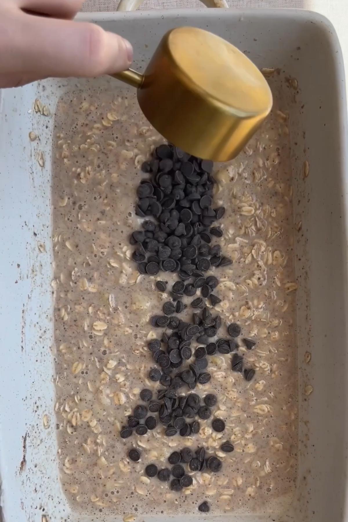Chocolate chips scattered over the oat batter in a baking dish.