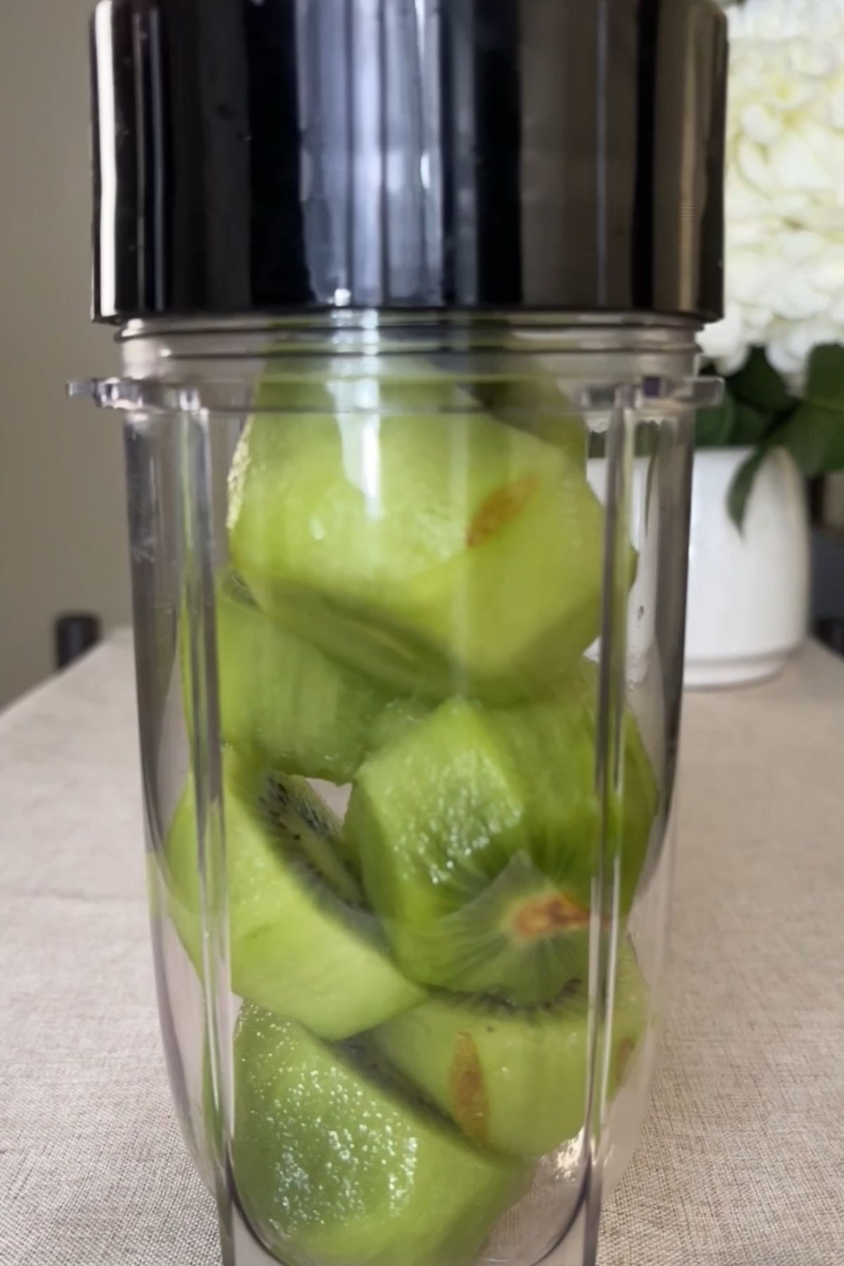 Peeled kiwi pieces added to a blender cup, ready to be blended.