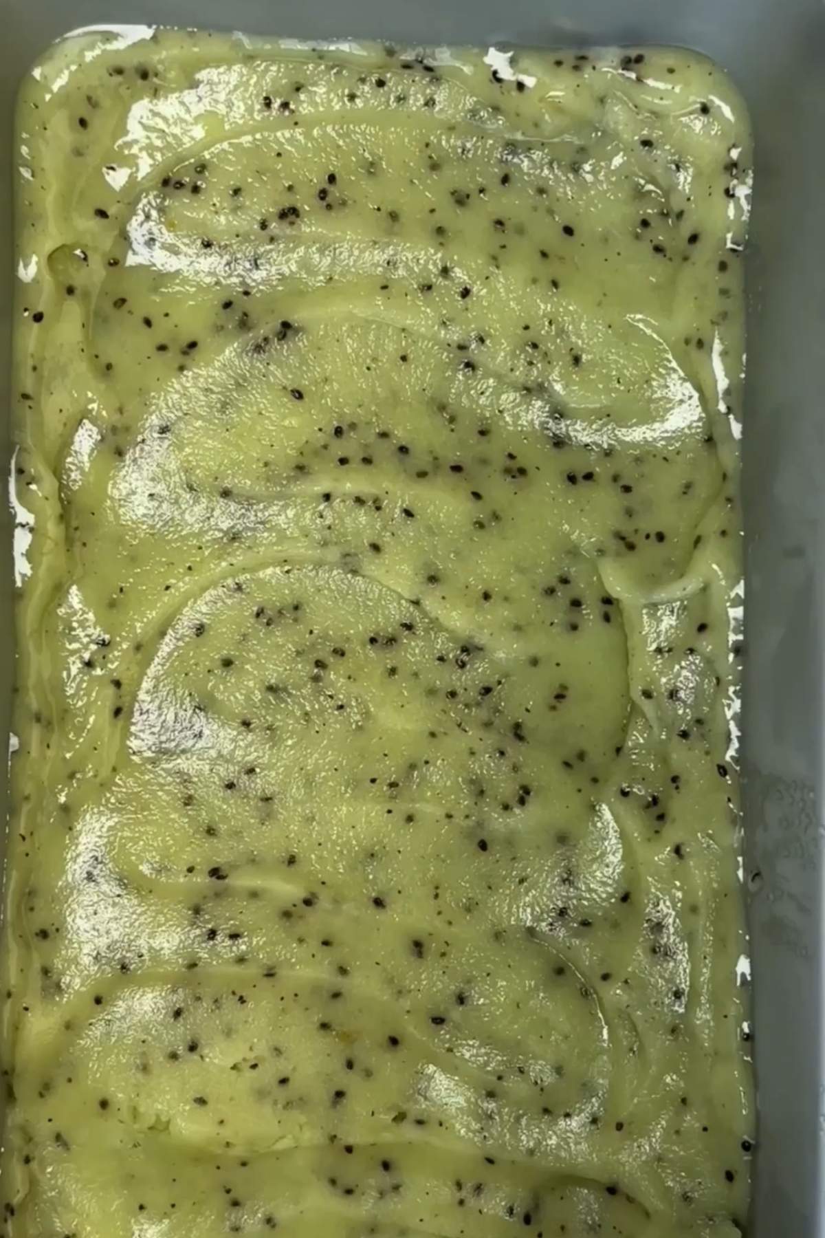 Frozen kiwi sorbet being sored in a container.