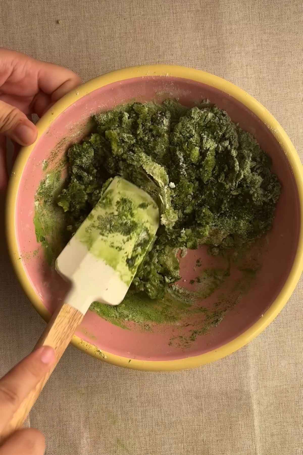 Folding sifted flour, matcha powder, and leavening into wet ingredients.