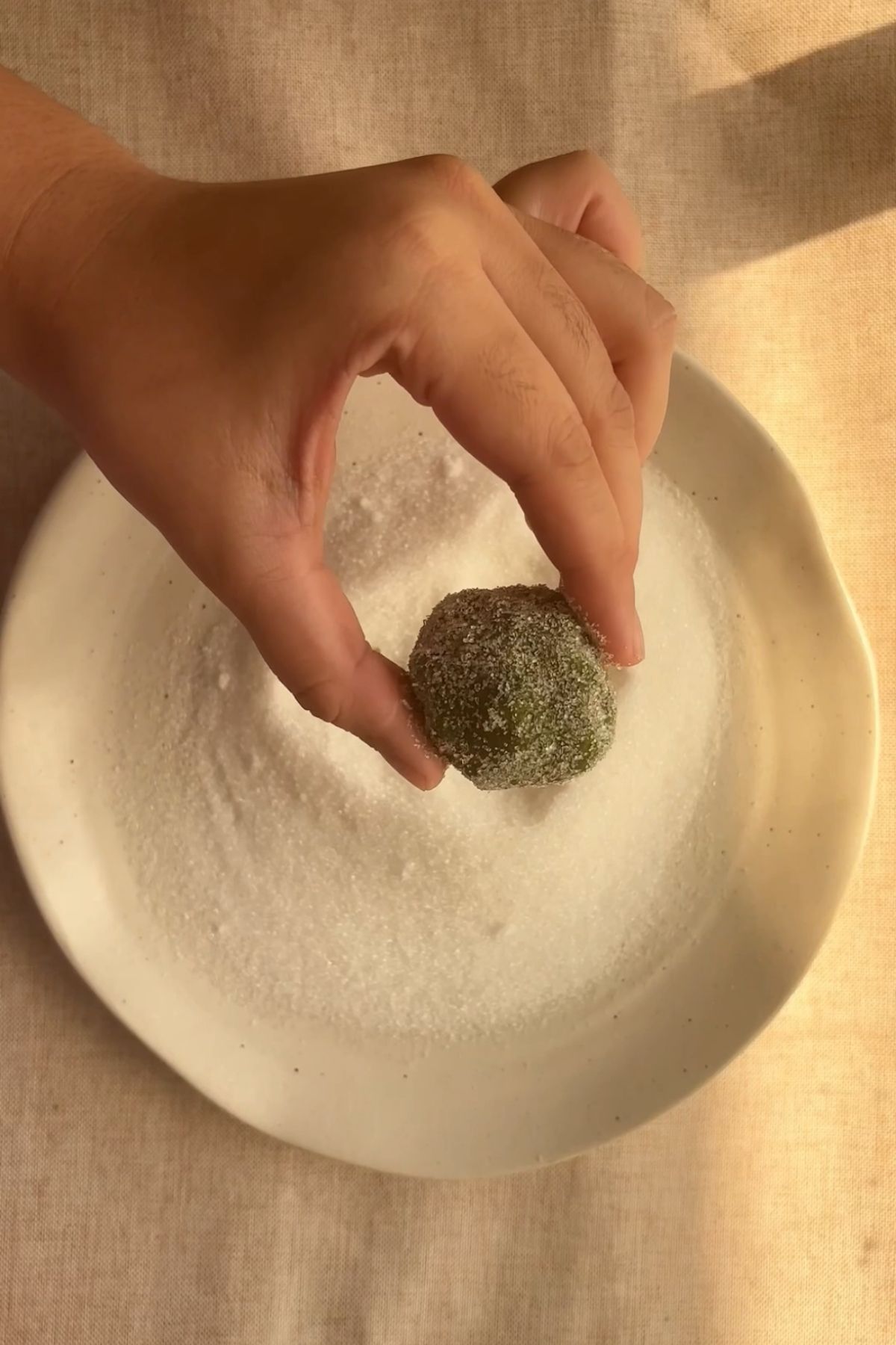 Rolled cookie dough balls in granulated sugar.