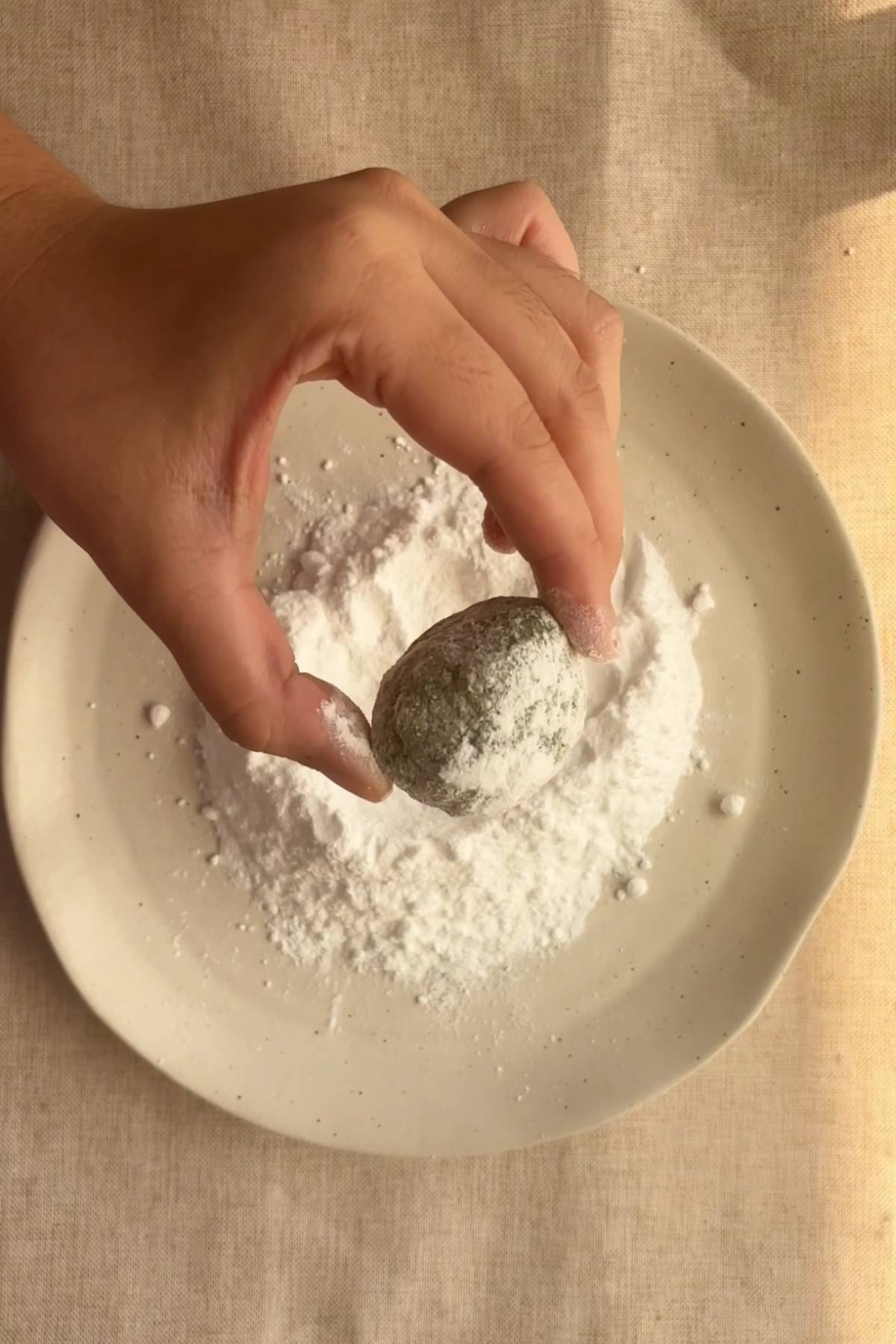 Rolling cookie dough balls in powdered sugar.
