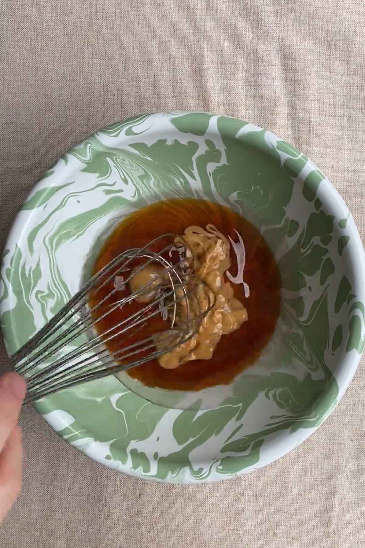 Maple syrup, melted coconut oil, almond butter, and vanilla being whisked together.