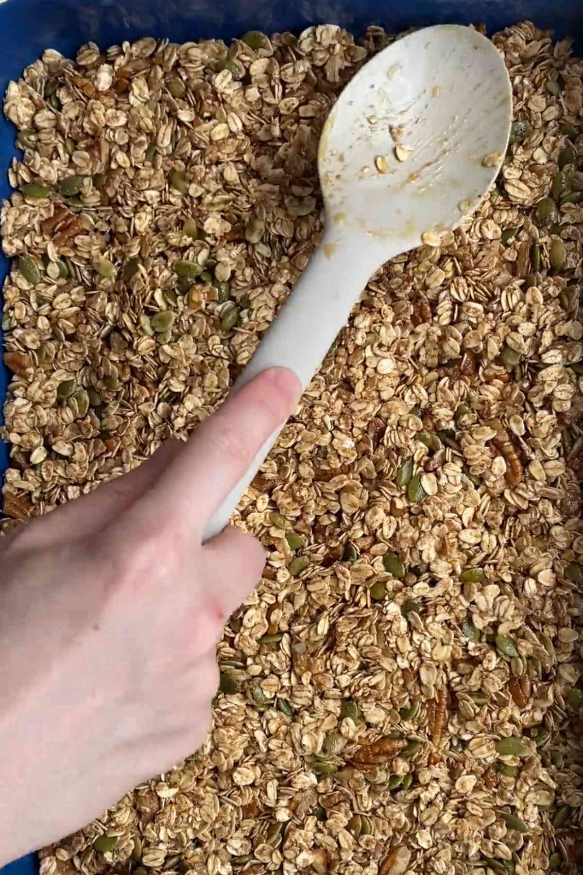 Granola spread evenly on a lined baking tray before baking.