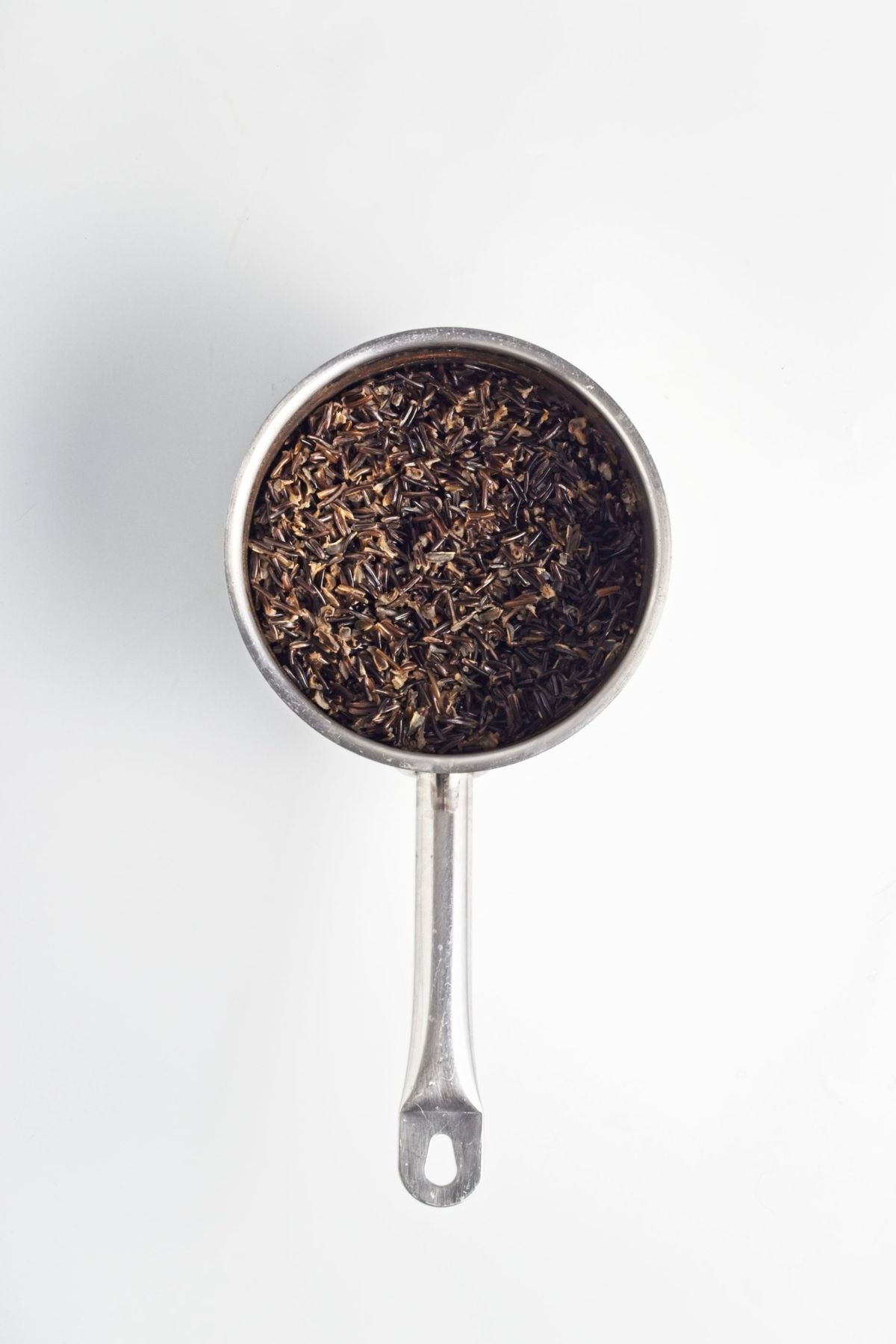 Cooked wild rice draining in a small metal saucepan.