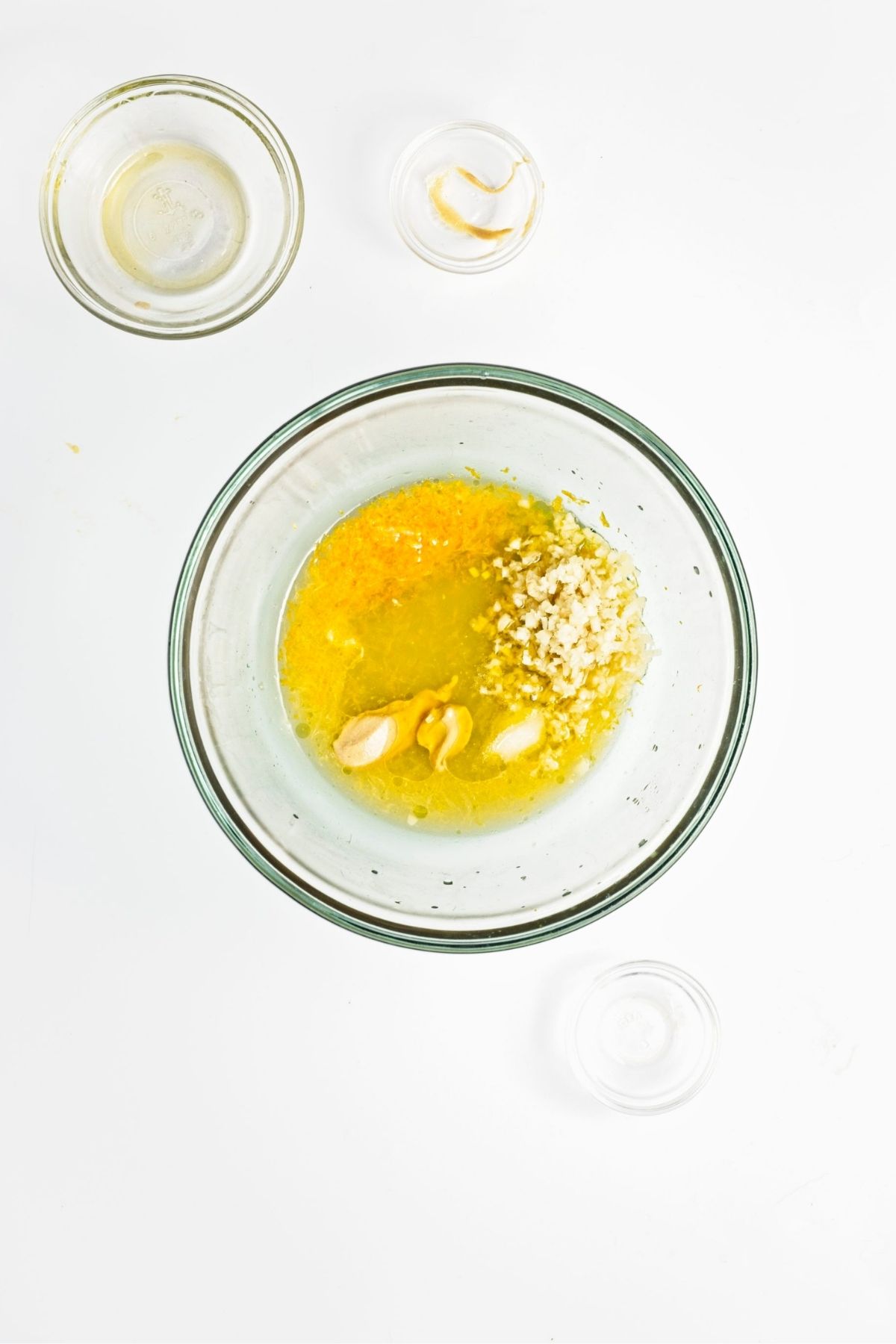Dressing ingredients with orange juice, ginger, mustard, and oil in a glass bowl.