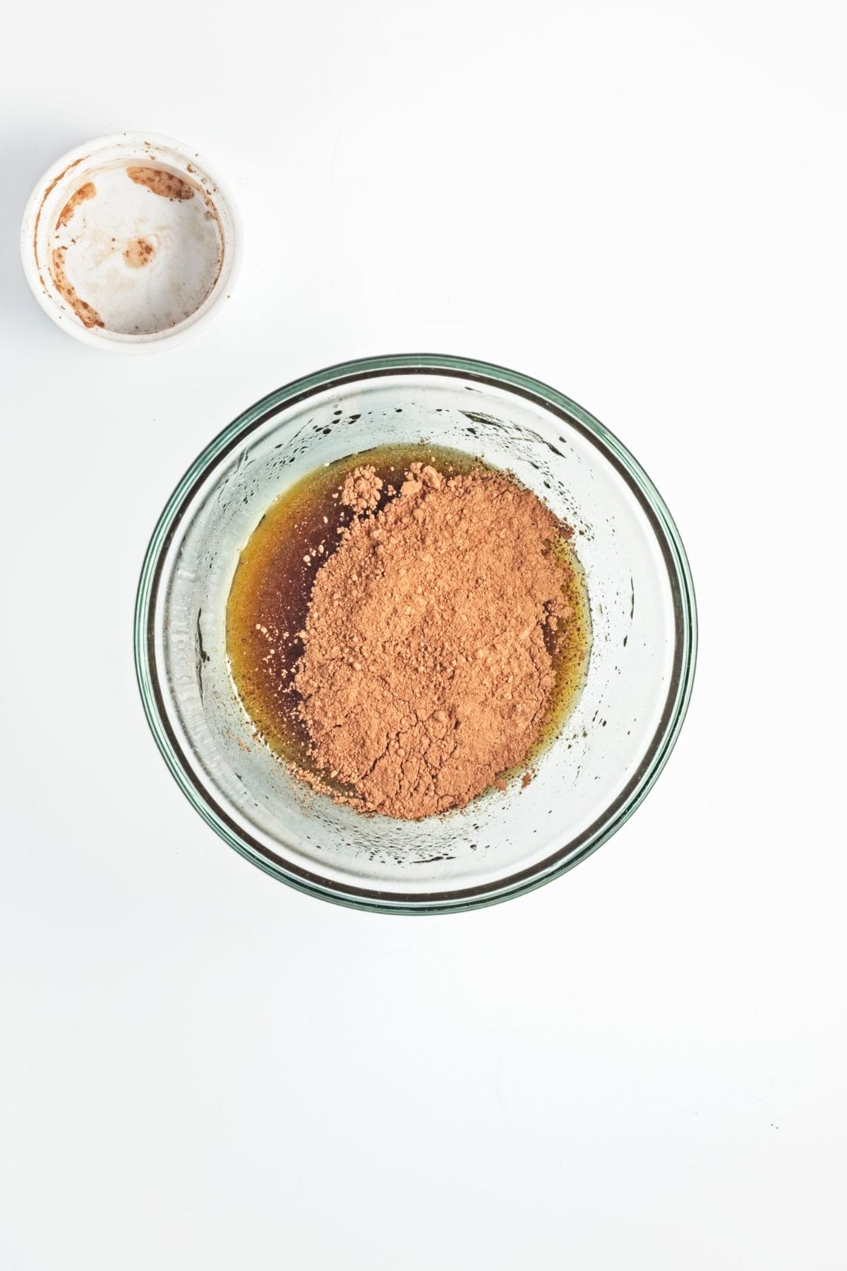 Cocoa powder added to the liquid mixture in a glass bowl.