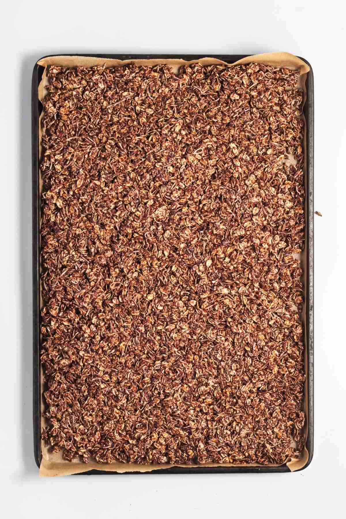 Chocolate oat mixture spread evenly on a lined baking tray.