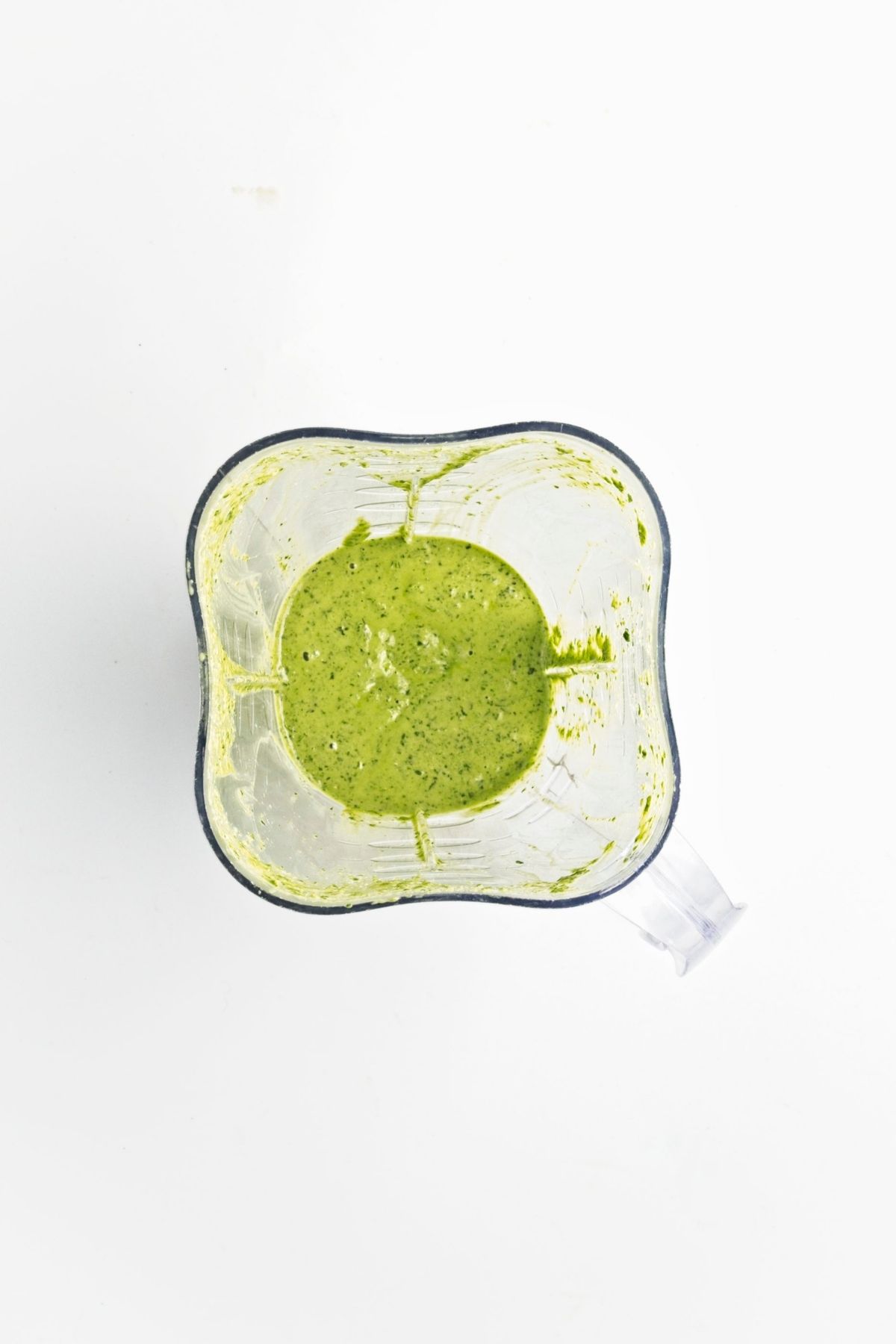 Herb and tahini dressing blended until smooth and creamy inside a blender.