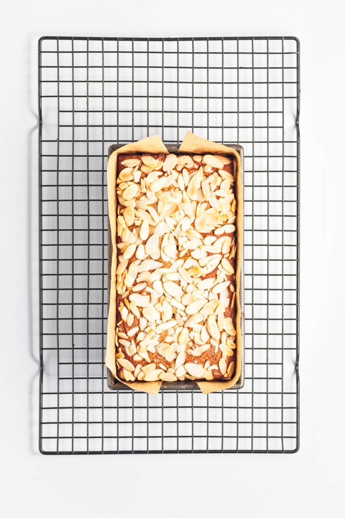 Baked lemon almond loaf cooling in the pan on a wire rack.