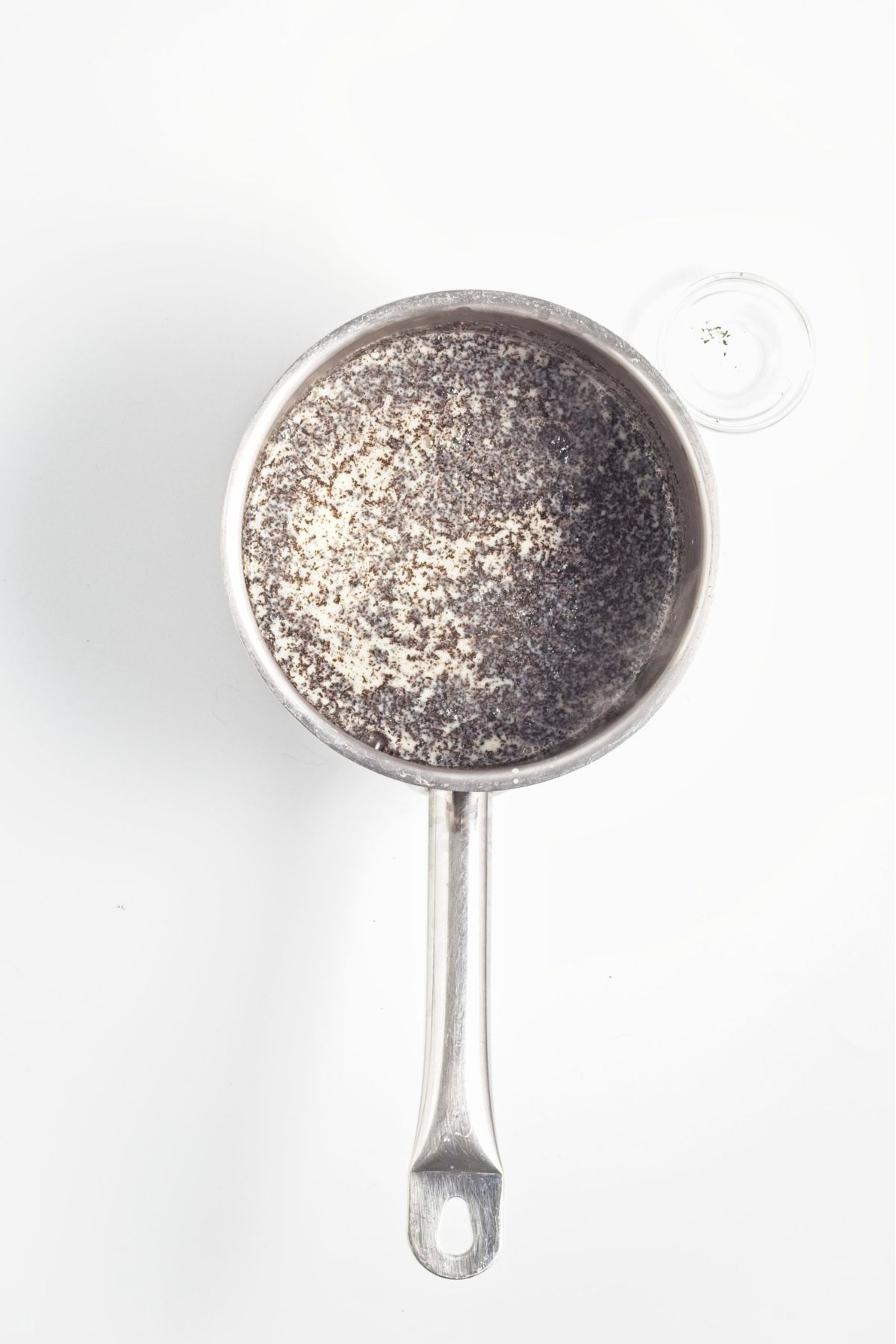 Earl Grey tea leaves steeping in warm oat milk in a small saucepan.