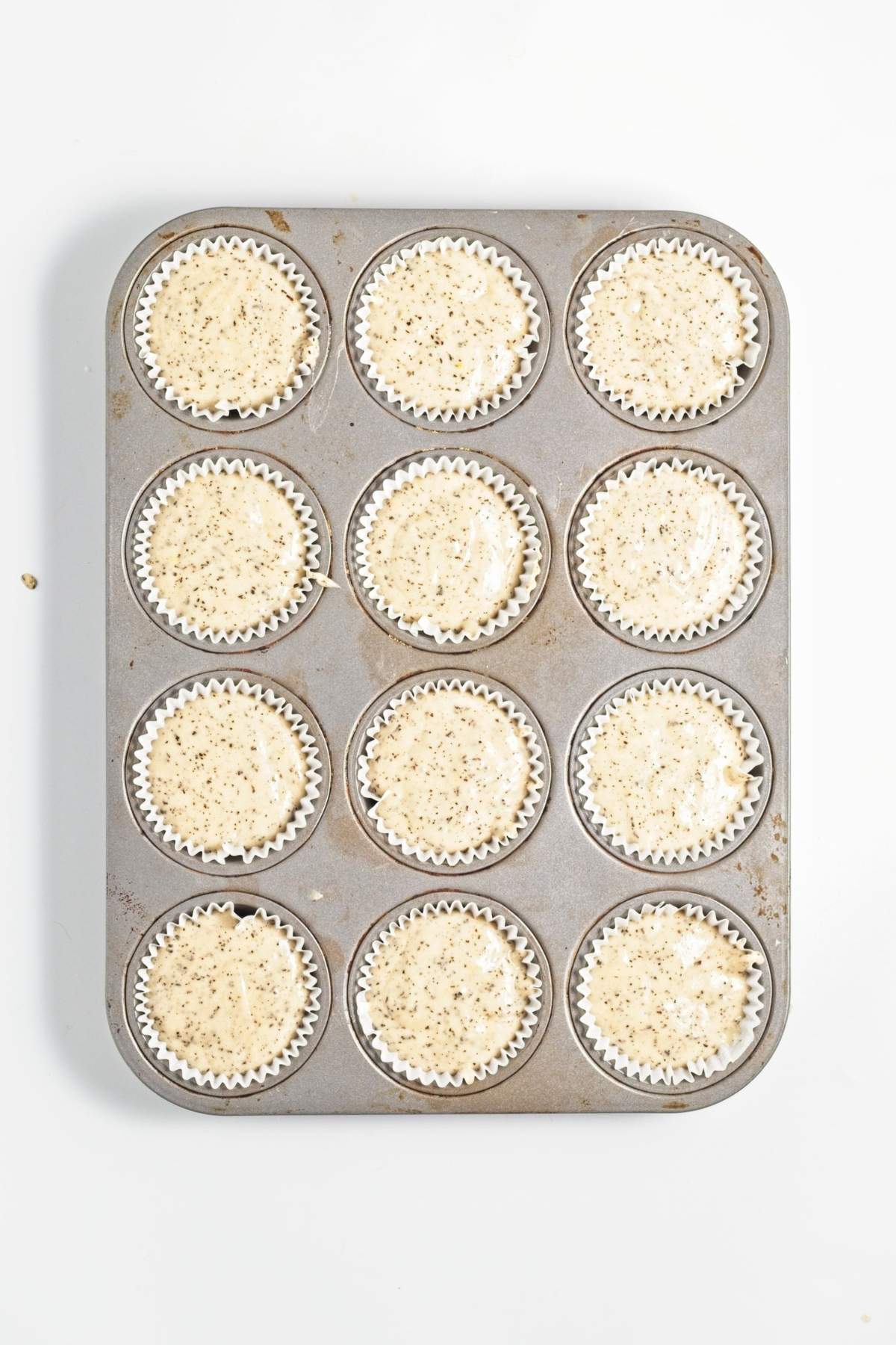 Cupcake batter portioned into lined muffin tin before baking.