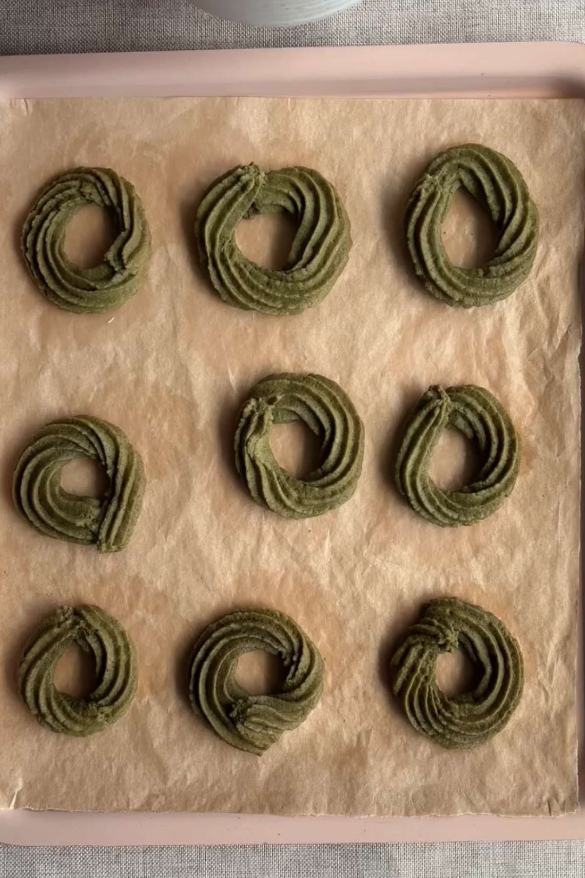 Perfectly baked matcha wreath cookies cooling on a baking paper.