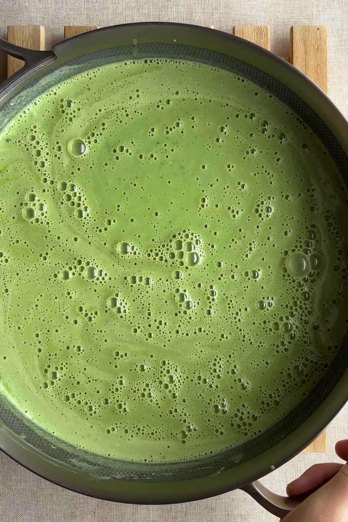 Green matcha mixture being poured into a pale cream base.