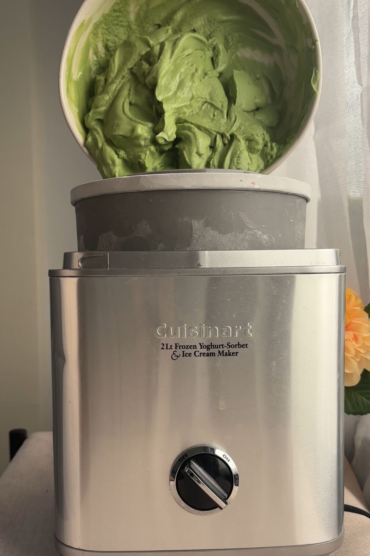 Thick green ice cream mixture churning inside an ice cream maker.