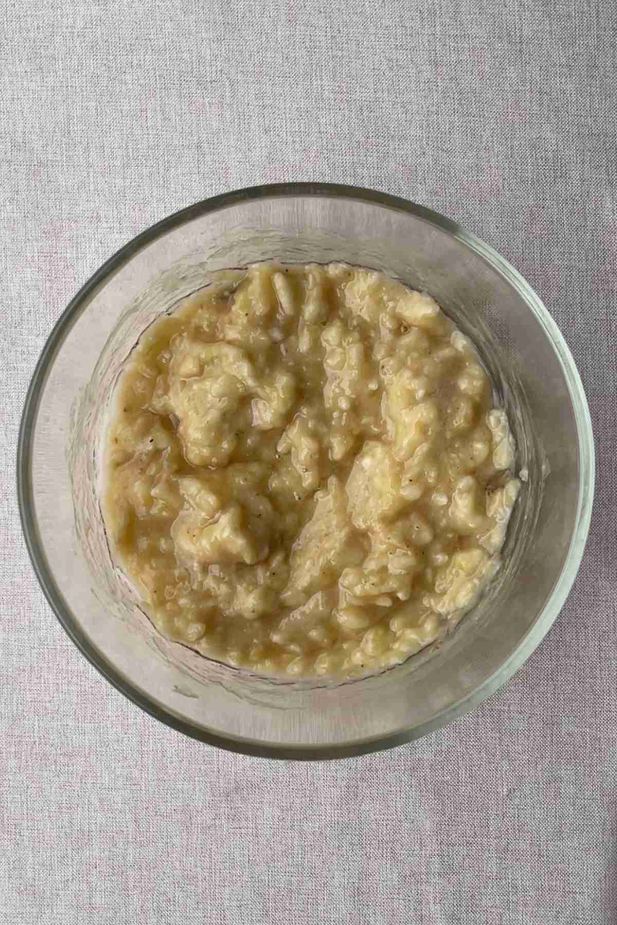 Mashed banana in a glass bowl ready to be mixed.