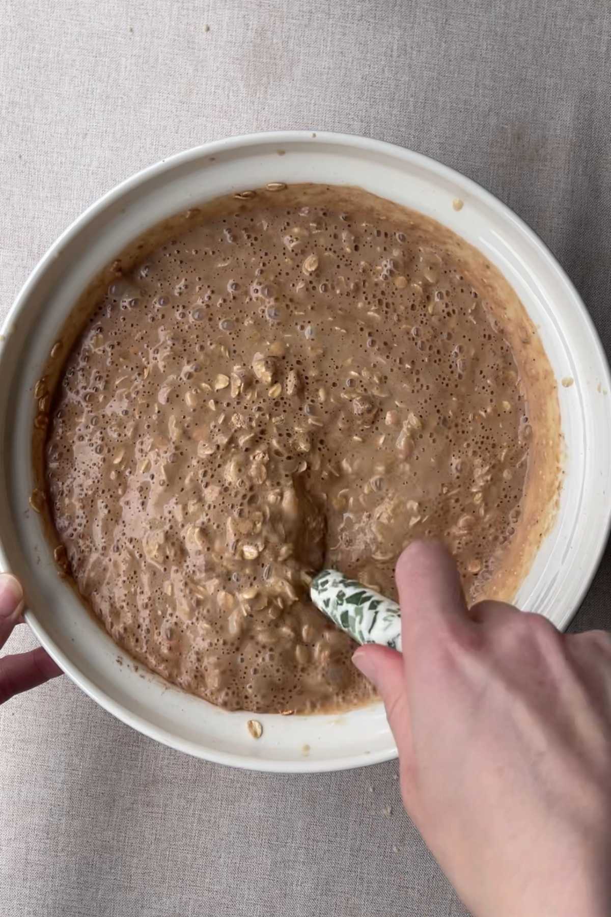 Stirring a bowl of oat batter with a spoon.