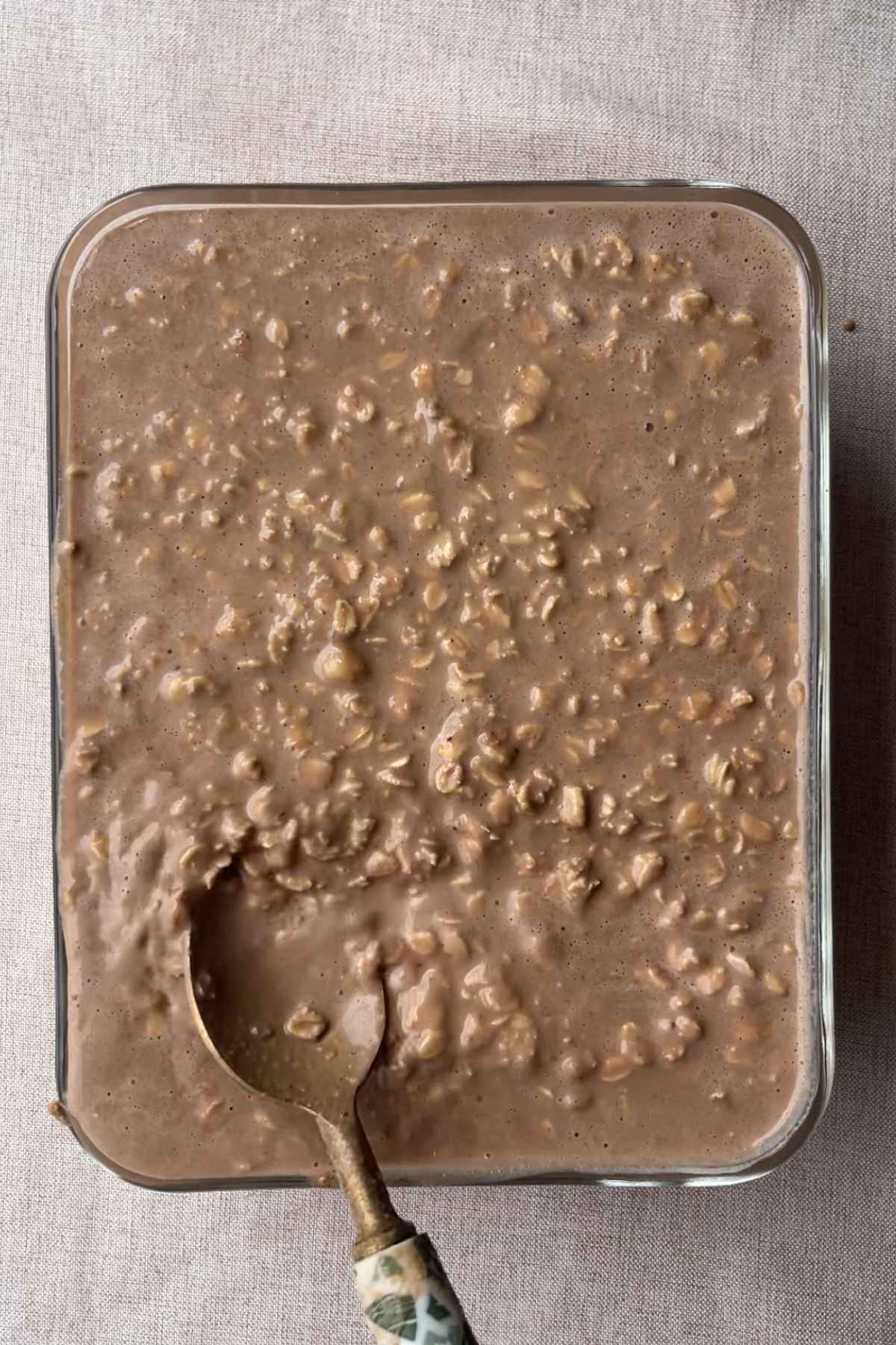 Unbaked oat batter spread in a rectangular baking dish with a spoon.