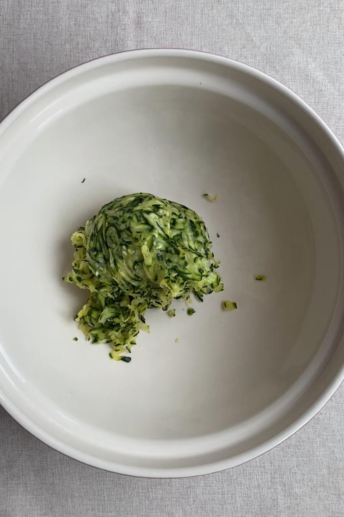 Squeezed grated zucchini resting in a bowl.