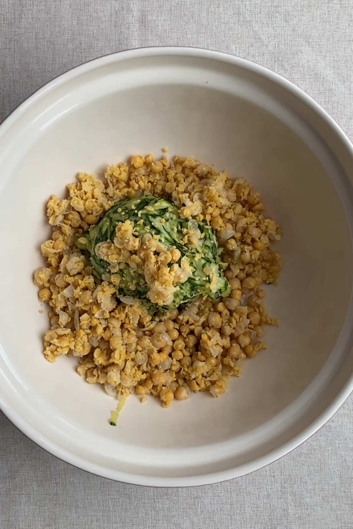 Mashed chickpeas and grated zucchini combined in a mixing bowl.