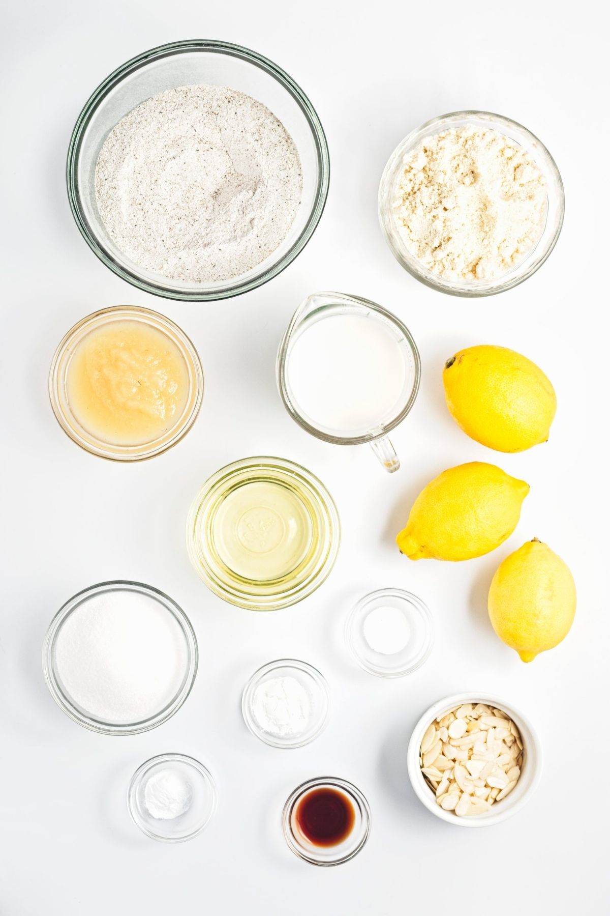 Measured ingredients for lemon almond loaf arranged on a white surface.