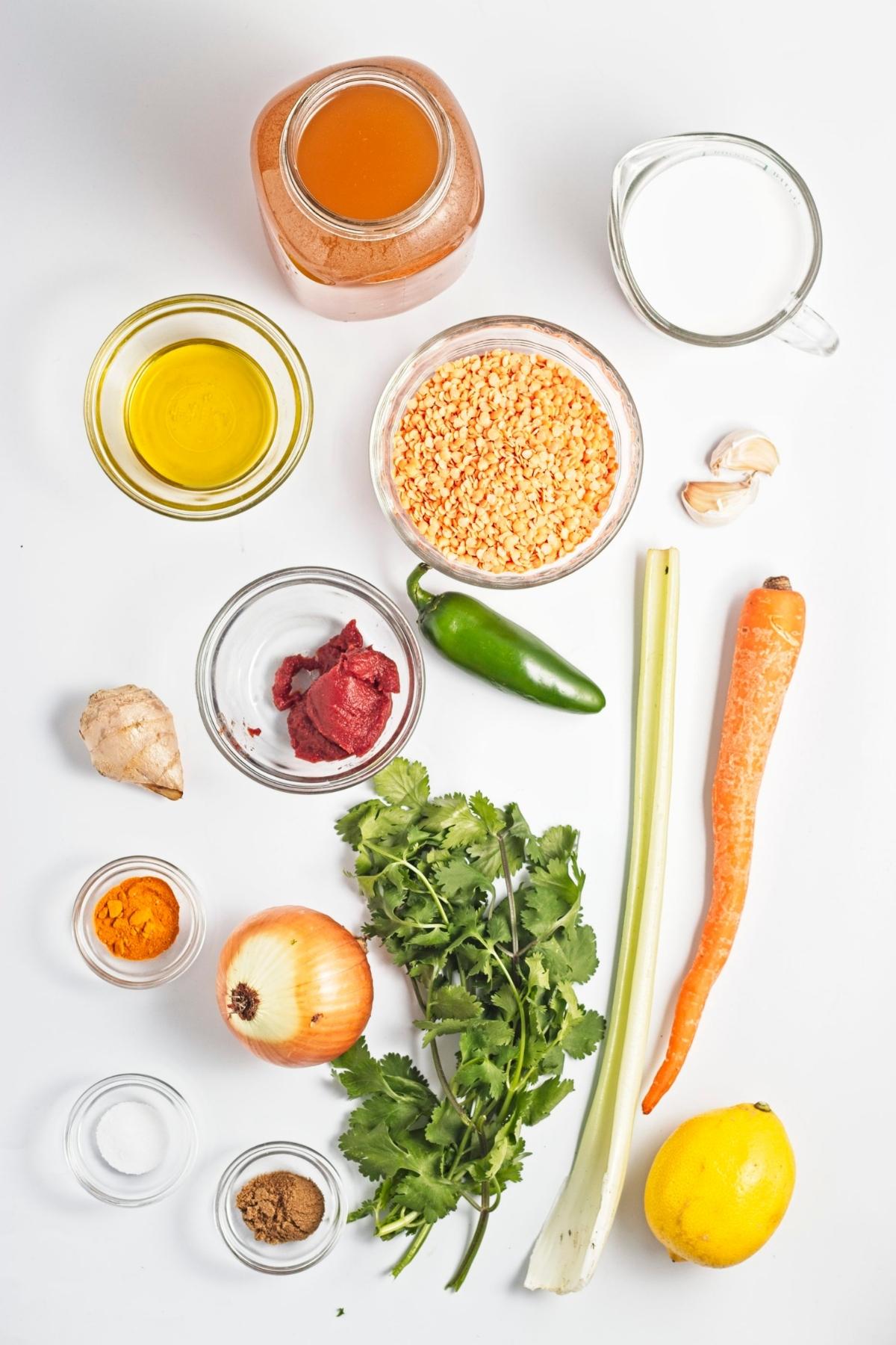 Overhead view of lentils, onion, carrot, celery, jalapeรฑo, garlic, ginger, spices, lemon, oil, and broth.