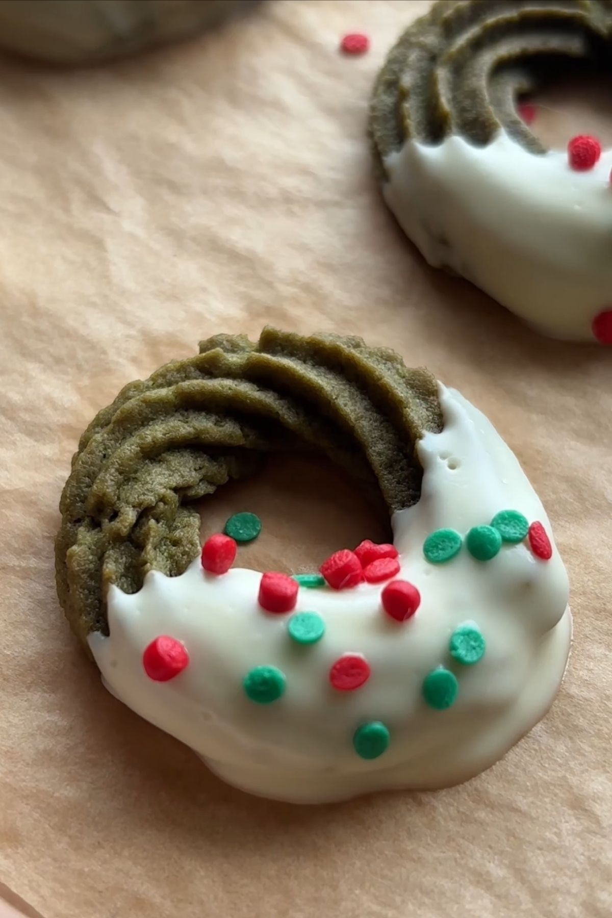 Close-up of a matcha wreath cookie with piped ridges and white chocolate dip.