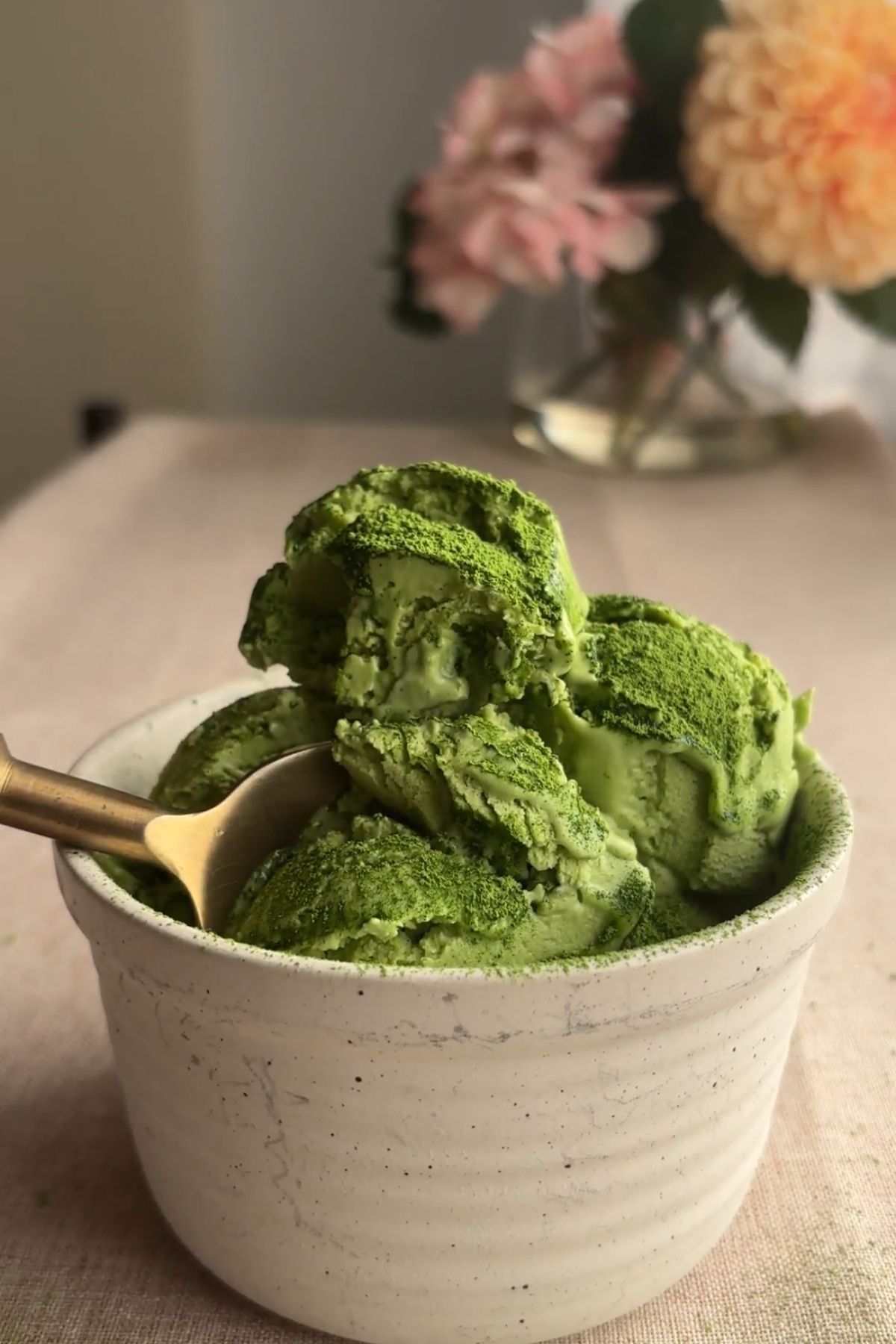 A spoon resting in a bowl of green ice cream.