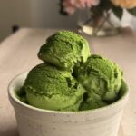 Three scoops of green ice cream stacked in a ceramic bowl.