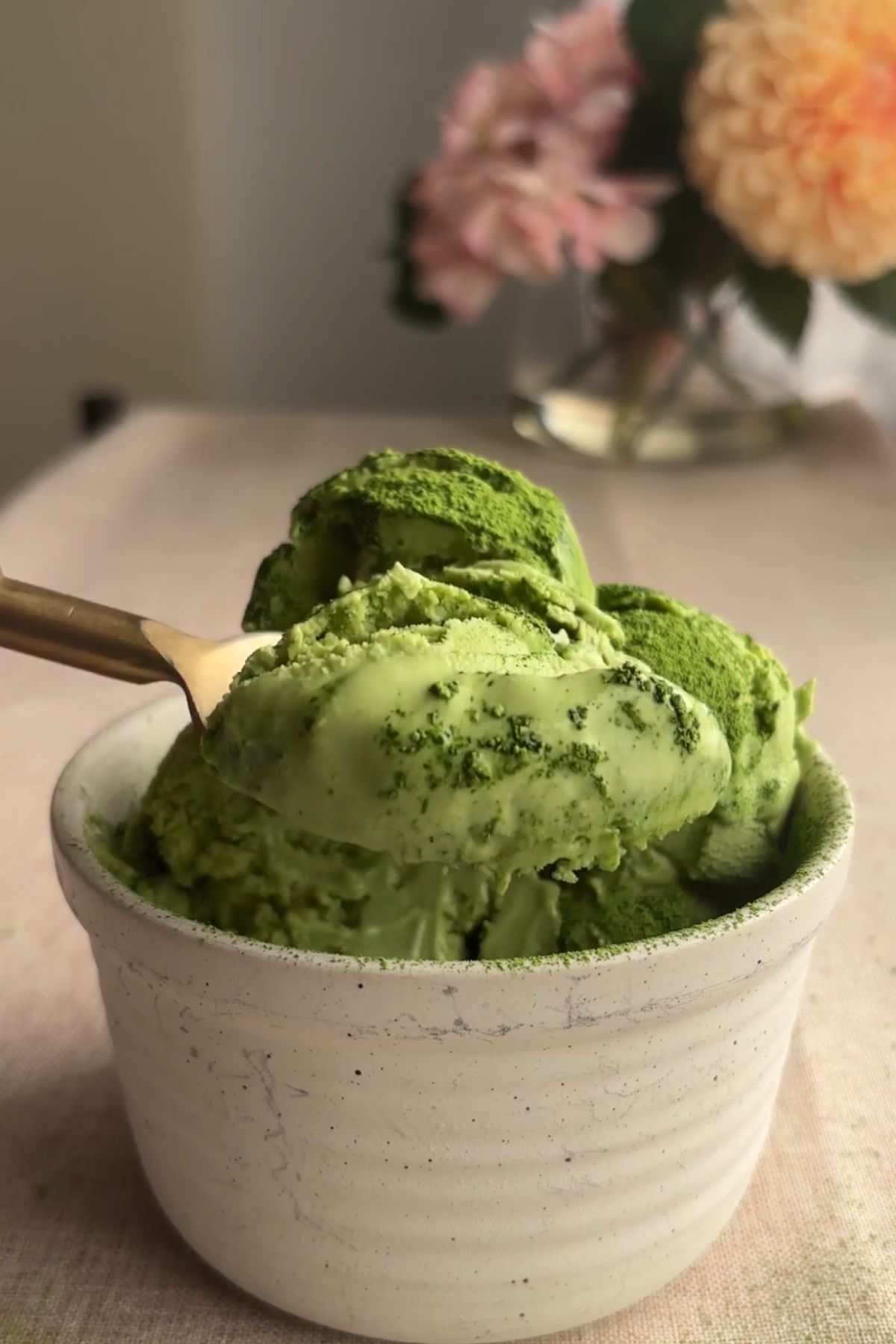 A spoon scooping green ice cream from a ceramic bowl.