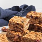 Baked oatmeal cookie bars cut into squares and arranged on parchment paper.
