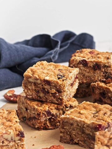 Baked oatmeal cookie bars cut into squares and arranged on parchment paper.