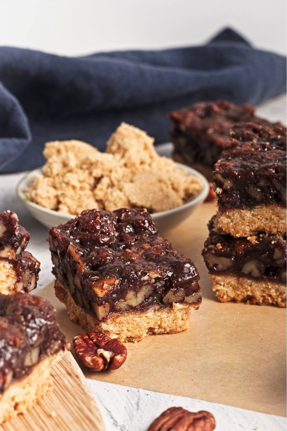 Close-up of sliced pecan bars on a wooden board with whole pecans nearby.